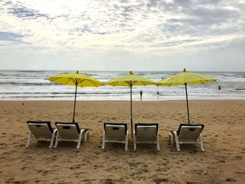 Deck chairs on beach against sky