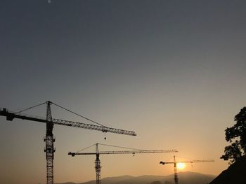 Low angle view of silhouette crane against clear sky during sunset