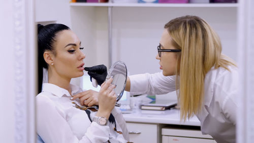 Clinic, cosmetology room, the doctor shows the patient a lip zone for injection of hyaluronic acid