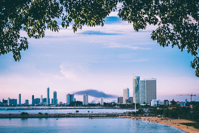 City at waterfront against cloudy sky