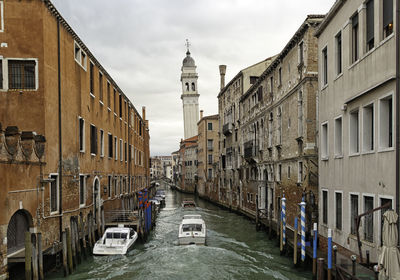 Canal amidst buildings against sky