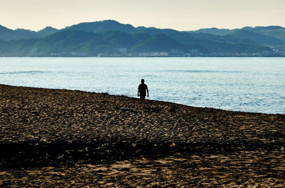Silhouette man looking at sea against sky