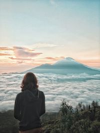 Rear view of woman looking at mountains against sky