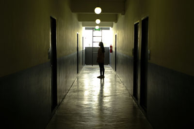 Rear view of man walking in corridor of building