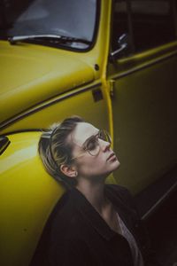 Young woman sitting by yellow car