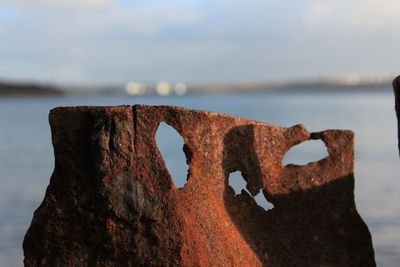 Close-up of rusty metal by sea against sky