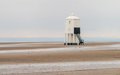 Lighthouse on beach against sky