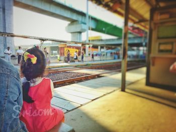 Rear view of girl standing by train at railroad station