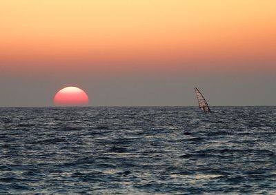 Sailboat sailing on sea against sky during sunset