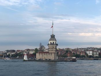 Buildings at waterfront against cloudy sky