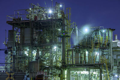 Low angle view of illuminated factory against sky at night