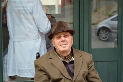 Portrait of smiling senior man sitting on chair outside shop