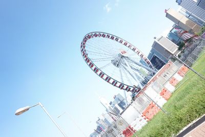 Low angle view of ferris wheel against buildings in city