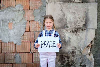 Portrait of girl holding poster against wall