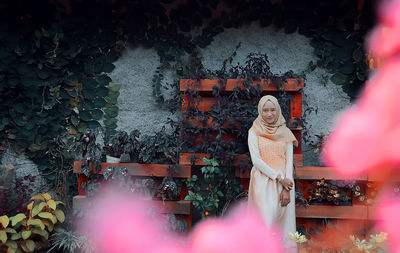 Portrait of young woman wearing hijab while standing against wall