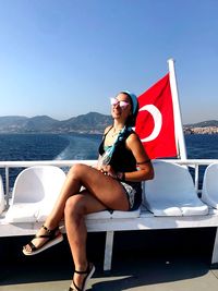 Portrait of young woman sitting on sea against sky