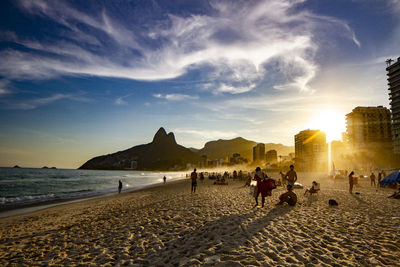 People on beach against sky during sunset