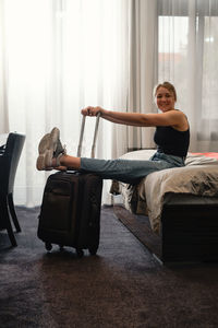 Woman taking off footwear in sunny hotel room on the bed. tourist relaxing on hotel room after