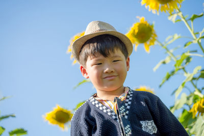 Portrait of cute smiling boy in hat against sky