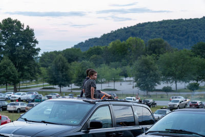 Woman by car against sky