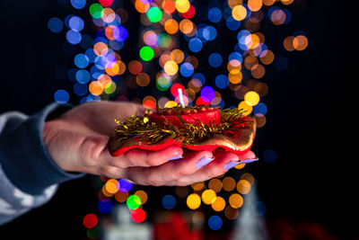 Close-up of hand holding illuminated christmas lights