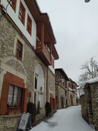 Snow covered houses amidst buildings against sky