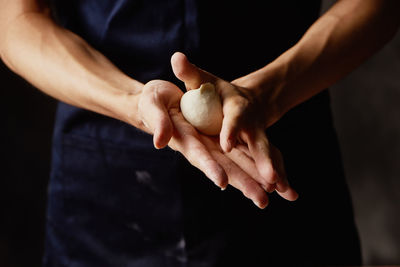 Midsection of person holding dough in bakery