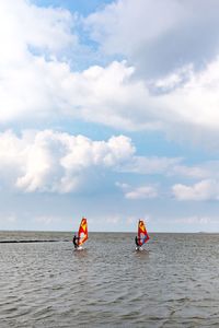 People windsurfing in sea against sky