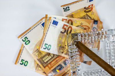 Close-up of banknotes with cigar over white background