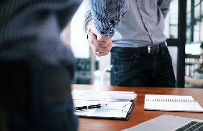 Midsection of businessmen shaking hands in office