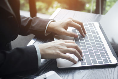 Midsection of man using laptop on table