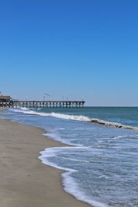 Scenic view of beach against clear blue sky