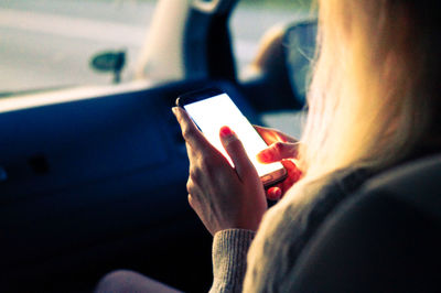 Midsection of woman using mobile phone while sitting in car