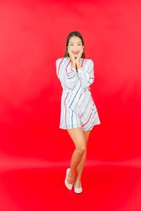 Full length of woman standing against red background