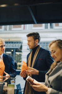 Business people discussing while holding food and drink in city