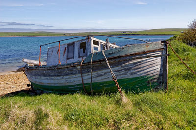 Abandoned boat on beach against sky