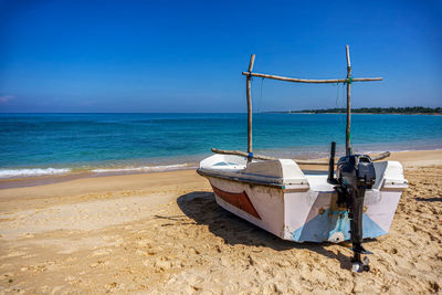 Lonely motor fishing boat on the sandy sunny beach of sri lanka. sun, sand, indian ocean and boat