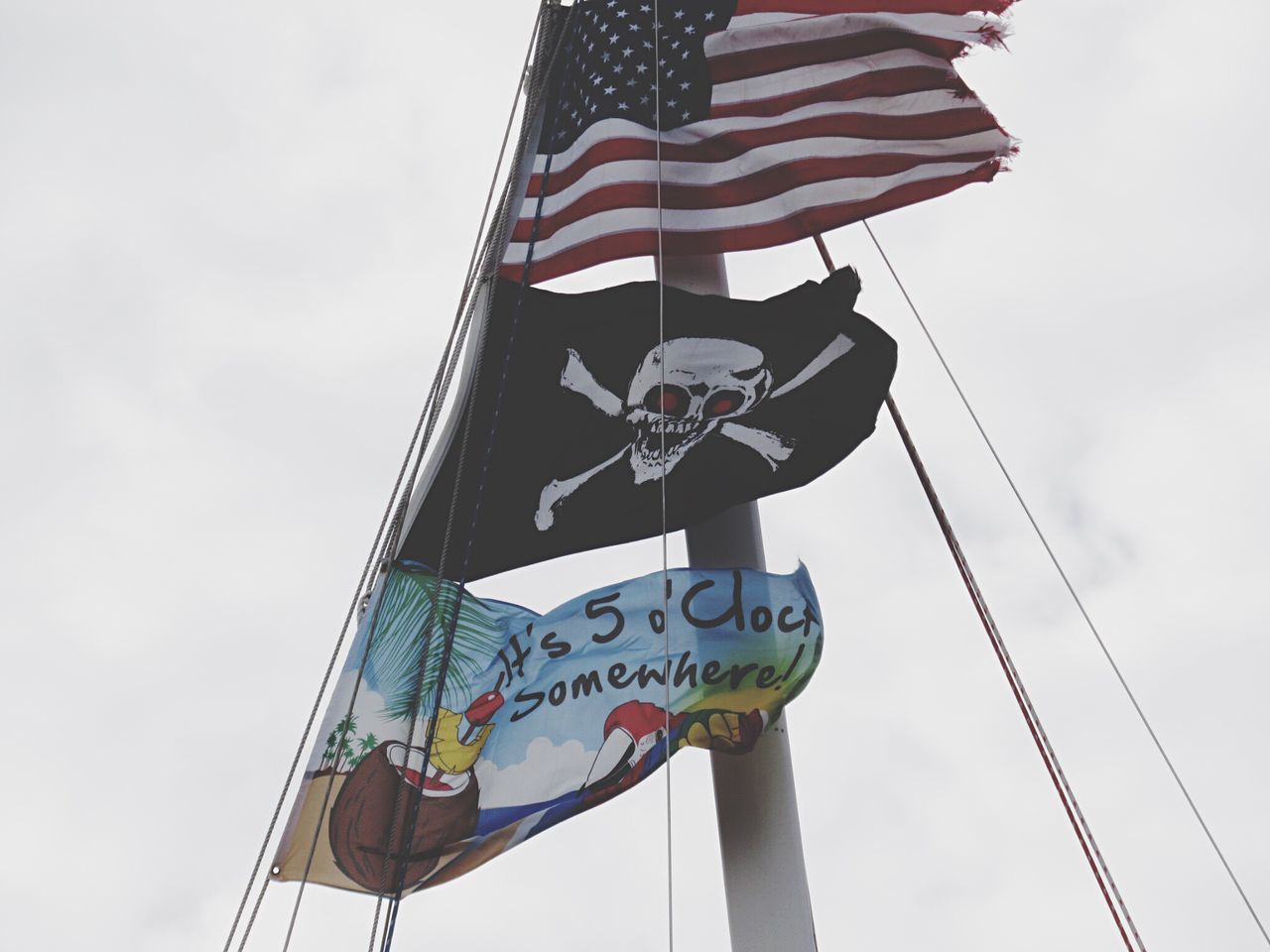 low angle view, identity, patriotism, flag, sky, national flag, american flag, pole, day, outdoors, wind, culture, communication, cloud - sky, no people, red, cloud, waving, flag pole, blue