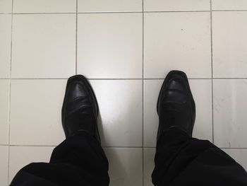 Low section of man standing on tiled floor