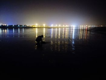 Silhouette man at beach against sky at night