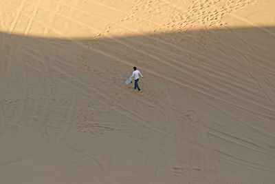 Aerial view of man walking on sand dune