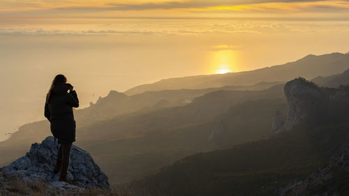 A girl stands on a mountain and looks at the sunset. atmospheric evening view of the mountains