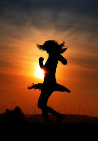 Low angle view of silhouette man jumping against sky during sunset