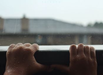 Close-up of hand on wet window