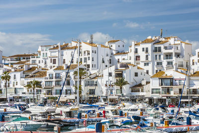 Sailboats moored on sea against buildings in city