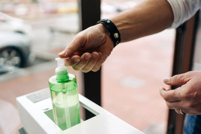 Close-up of man holding glass bottle on table