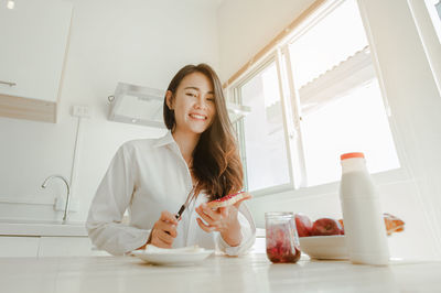 Portrait of smiling young woman against clear sky