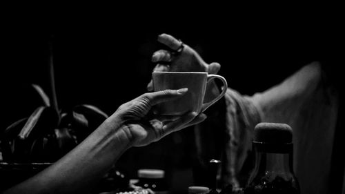 Close-up of hand holding coffee cup in darkroom