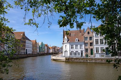 Buildings by river against sky