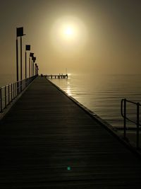 Pier over sea against sky during sunset